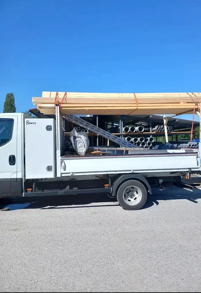 Camion plateau chargé de bois de charpente et de matériaux pour un chantier de couverture