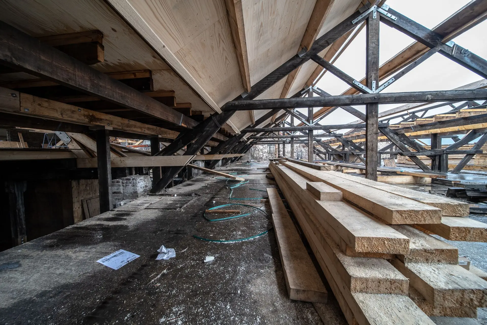 Chantier de charpente avec fermes, poutres métalliques et bois de construction stocké