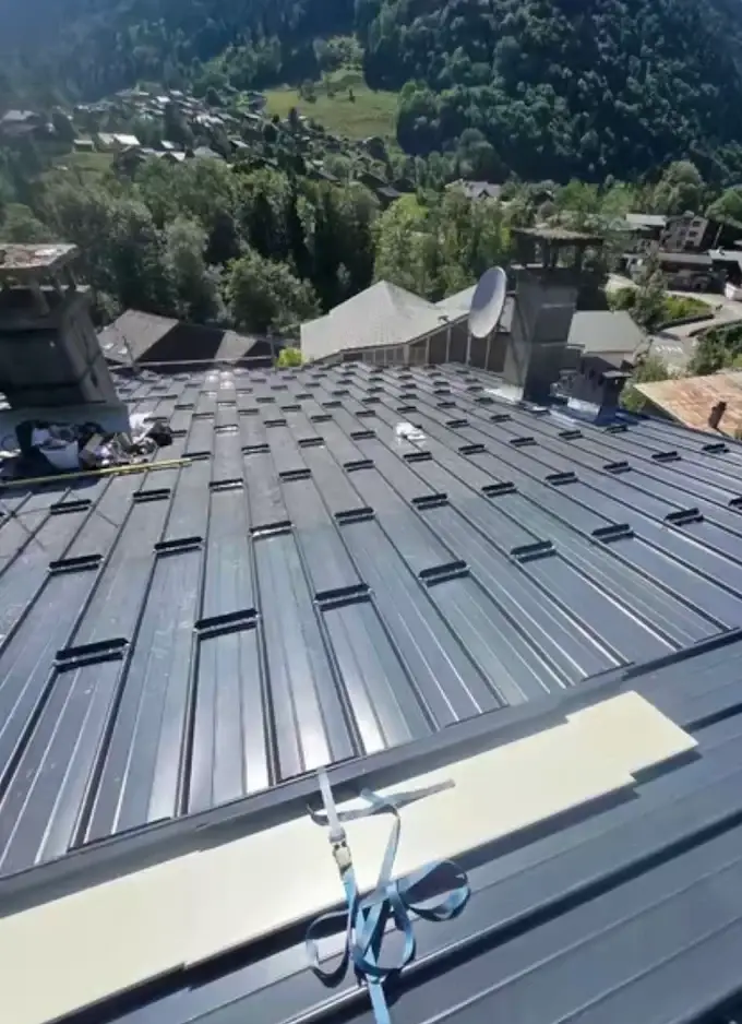 Couverture en bac acier anthracite à joints debout avec arrêts de neige sur un chalet de montagne