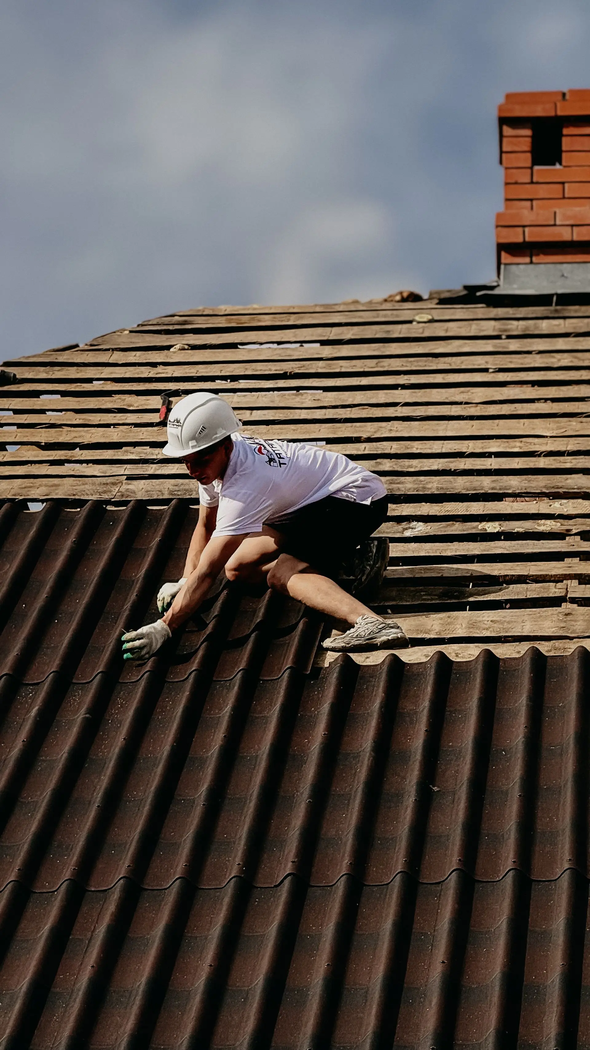Couvreur déposant l’ancienne couverture ondulée d’une toiture