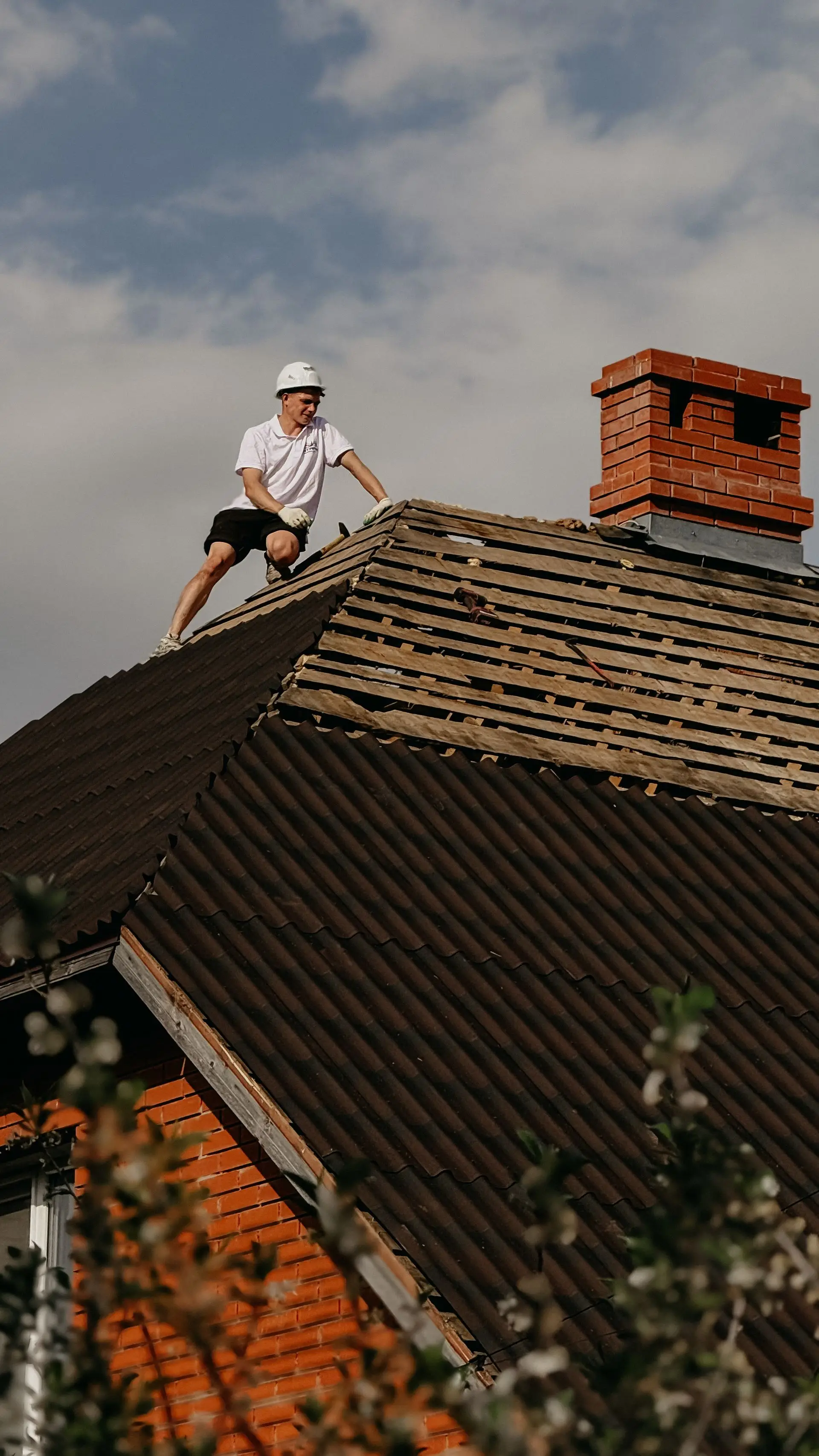 Couvreur sur un toit près d’une cheminée en briques