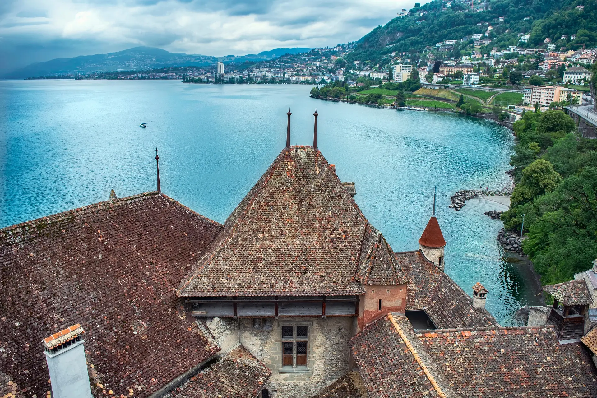 Toitures en tuiles d’un château au bord d’un lac, vue aérienne et montagnes