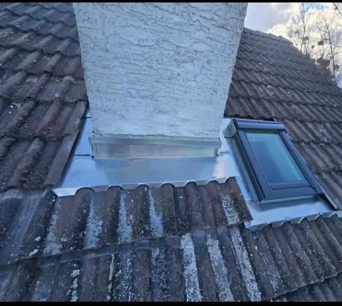 Solin en zinc autour d’une cheminée et d’une fenêtre de toit sur une couverture en tuiles